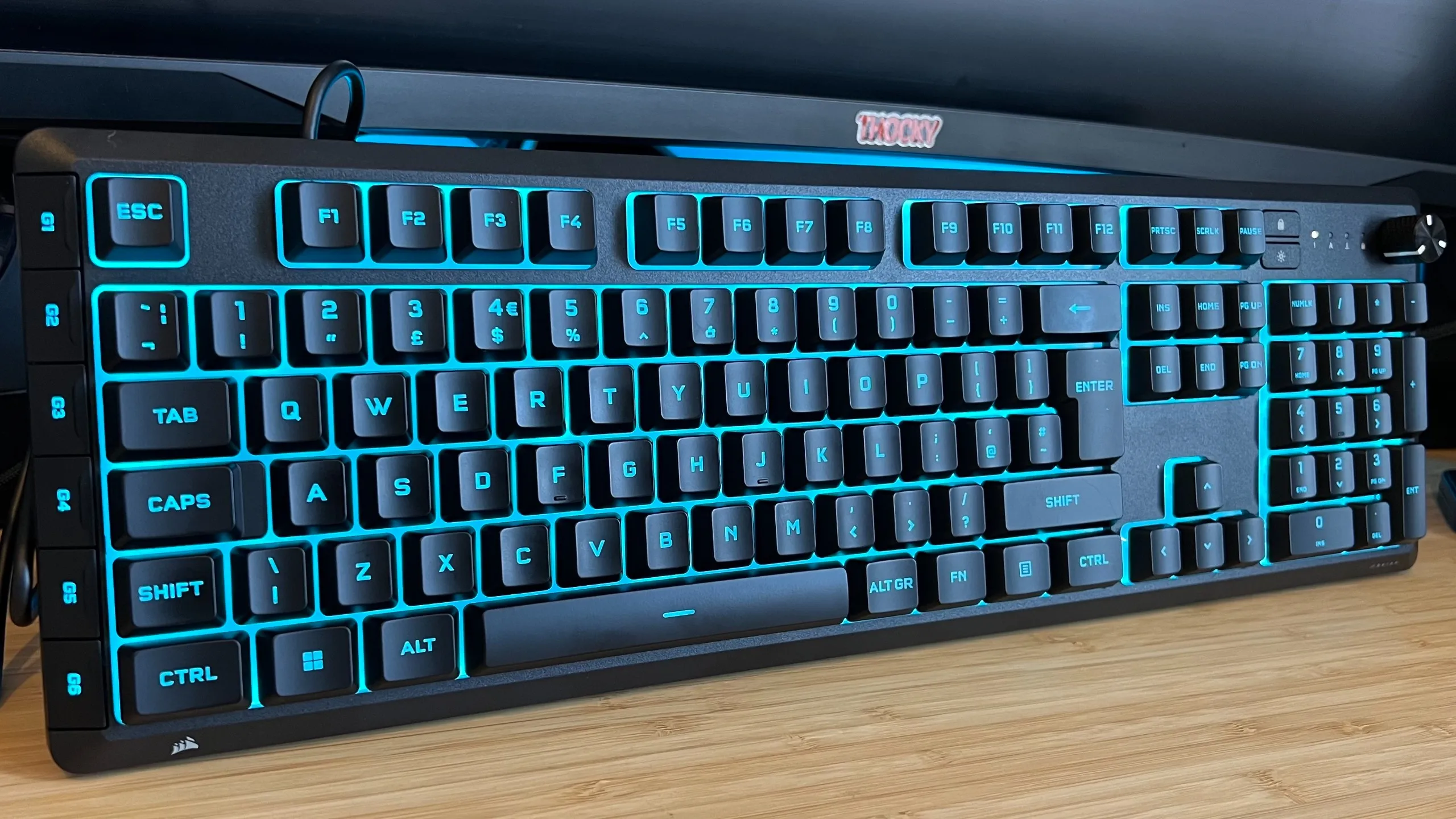 Corsair Skiff 100 Plus gaming keyboard standing upright on a wooden desk